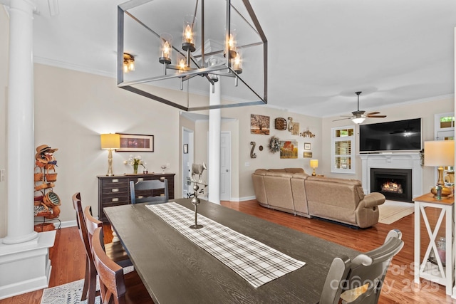 149 Harbor Landing Dr, Mooresville, NC 28117 - dining space featuring ornate columns, a warm lit fireplace, a ceiling fan, wood finished floors, and crown molding