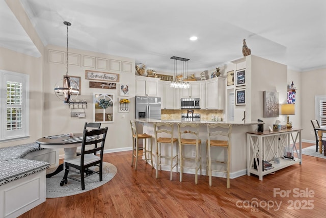 149 Harbor Landing Dr, Mooresville, NC 28117 - kitchen featuring stainless steel appliances, a chandelier, light stone counters, wood finished floors, and a breakfast bar area