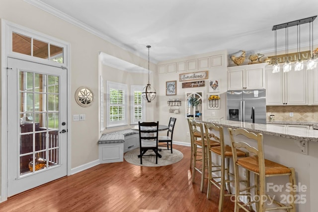 149 Harbor Landing Dr, Mooresville, NC 28117 - kitchen with stainless steel fridge, a kitchen bar, wood finished floors, crown molding, and light stone counters
