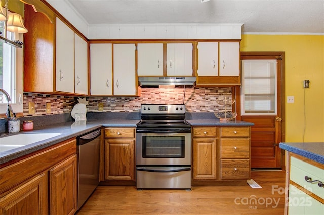 1405 8th Ave NW, Conover, NC 28613 - kitchen with under cabinet range hood, appliances with stainless steel finishes, light wood-style floors, tasteful backsplash, and dark countertops