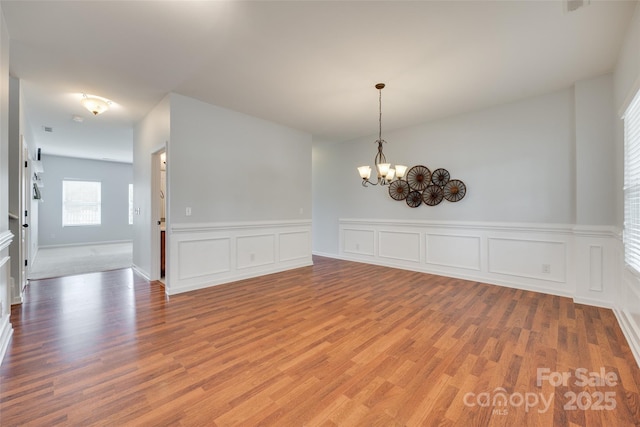 1412 Afternoon Sun Rd, Matthews, NC 28104 - unfurnished dining area featuring wood finished floors, a chandelier, wainscoting, and a decorative wall