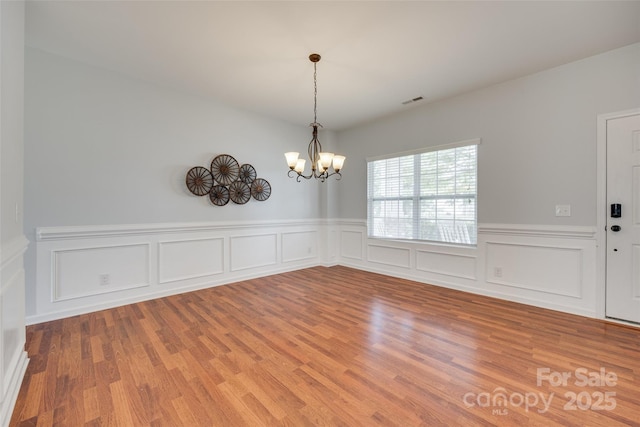 1412 Afternoon Sun Rd, Matthews, NC 28104 - unfurnished dining area with a chandelier, wood finished floors, a wainscoted wall, and a decorative wall