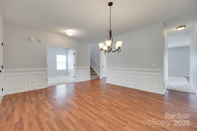 1412 Afternoon Sun Rd, Matthews, NC 28104 - unfurnished dining area with wood finished floors, stairs, a chandelier, wainscoting, and a decorative wall