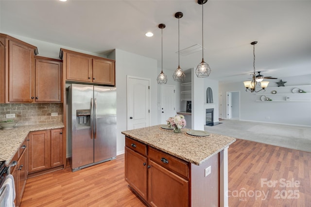 1412 Afternoon Sun Rd, Matthews, NC 28104 - kitchen featuring stainless steel refrigerator with ice dispenser, a glass covered fireplace, brown cabinets, decorative light fixtures, and recessed lighting