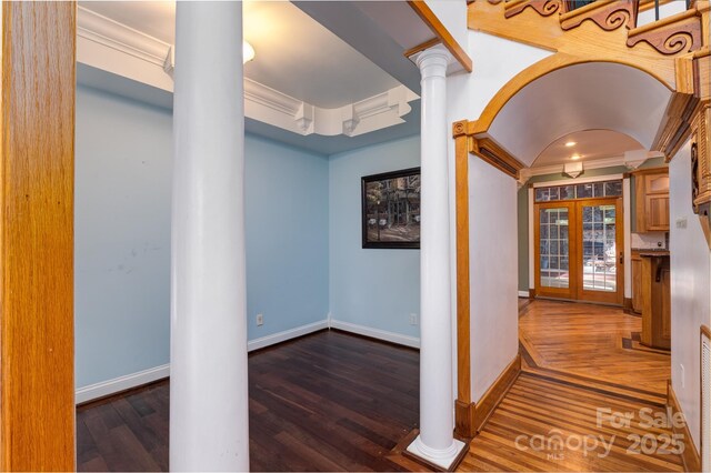hall with ornamental molding, decorative columns, dark wood-style flooring, baseboards, and french doors