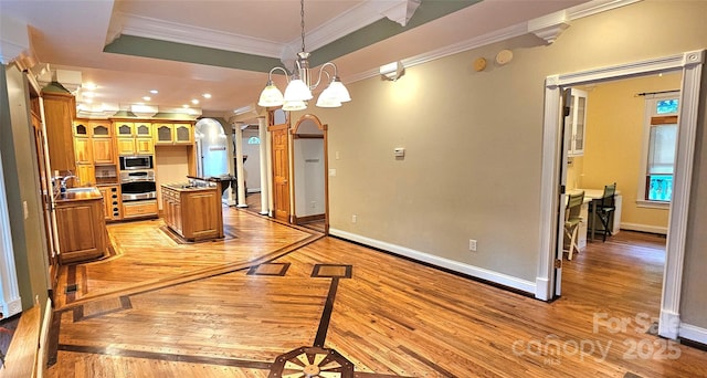 kitchen featuring appliances with stainless steel finishes, ornamental molding, light wood-style floors, baseboards, and a sink