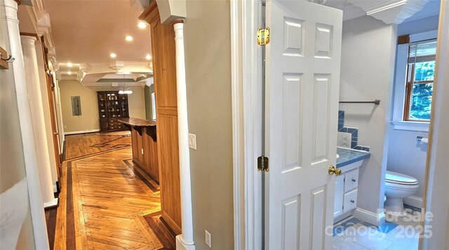 hall featuring crown molding, baseboards, light wood-style flooring, and recessed lighting