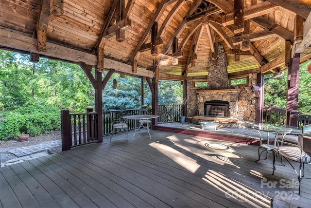 wooden terrace featuring an outdoor stone fireplace and a gazebo