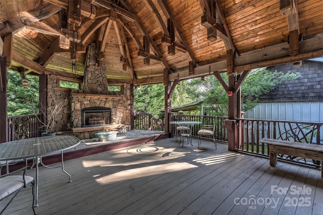 deck featuring an outdoor stone fireplace, a gazebo, and outdoor dining area
