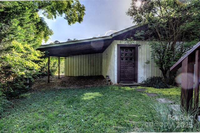 property entrance with a carport and a lawn