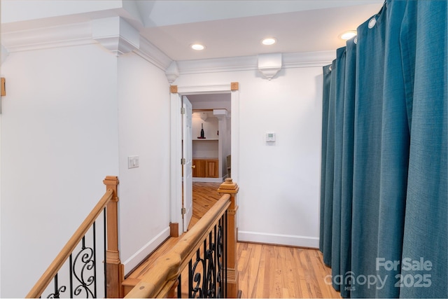 corridor with light wood finished floors, an upstairs landing, crown molding, baseboards, and recessed lighting