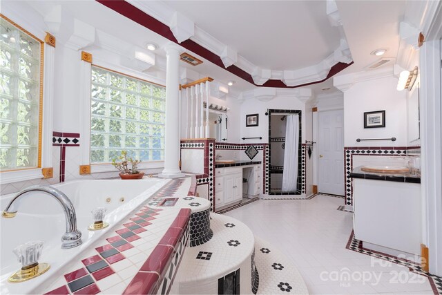 full bath featuring decorative columns, crown molding, vanity, a jetted tub, and recessed lighting