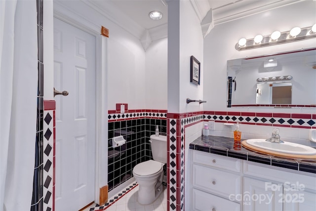 bathroom featuring toilet, tile patterned floors, tile walls, a wainscoted wall, and vanity