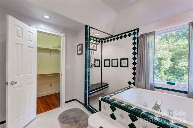 full bath featuring a shower stall, a garden tub, a walk in closet, recessed lighting, and tile patterned flooring