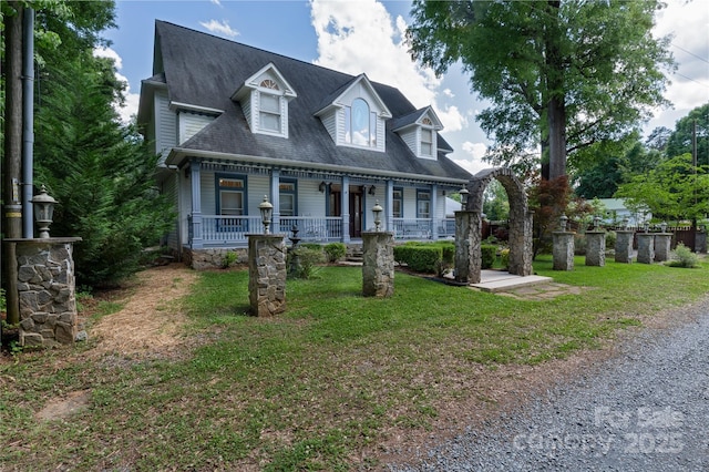 new england style home featuring a porch and roof with shingles