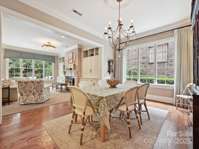 6128 Fletcher Cir, Charlotte, NC 28226 - dining room with a chandelier, crown molding, a warm lit fireplace, baseboards, and light wood-type flooring