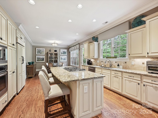 6128 Fletcher Cir, Charlotte, NC 28226 - kitchen with a sink, ornamental molding, cream cabinetry, a kitchen island, and light wood-type flooring