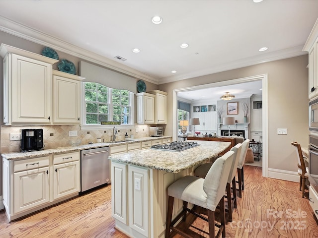 6128 Fletcher Cir, Charlotte, NC 28226 - kitchen featuring appliances with stainless steel finishes, a kitchen island, light wood-type flooring, a kitchen bar, and light stone countertops