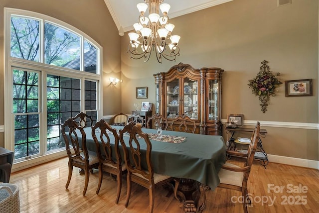 dining room featuring ornamental molding, vaulted ceiling, a chandelier, wood finished floors, and baseboards