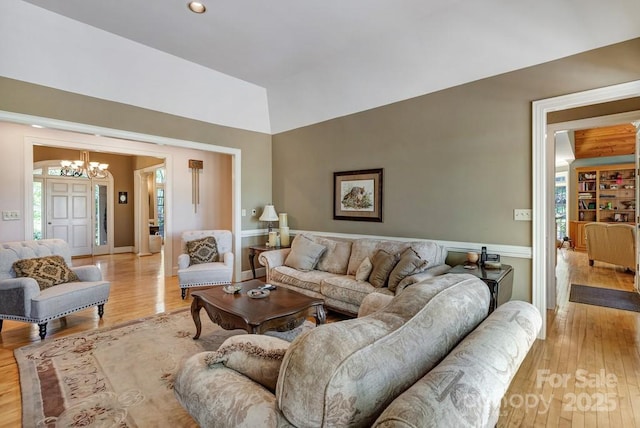 living room featuring a chandelier, light wood finished floors, plenty of natural light, recessed lighting, and vaulted ceiling