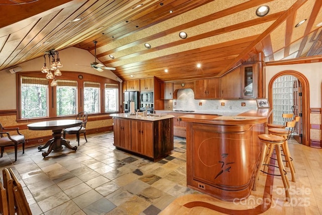 kitchen with lofted ceiling, stainless steel refrigerator with ice dispenser, a sink, built in microwave, and light countertops