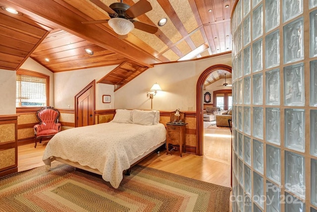 bedroom featuring a wainscoted wall, vaulted ceiling, wood finished floors, multiple windows, and wooden ceiling