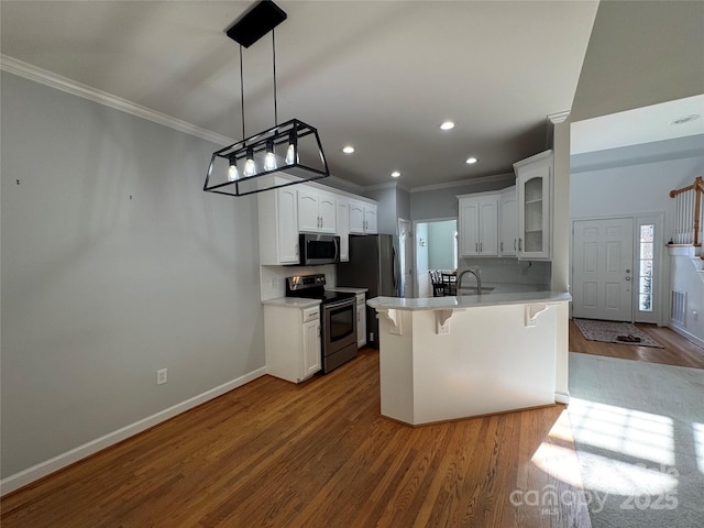 kitchen with stainless steel appliances, wood finished floors, a breakfast bar, a peninsula, and crown molding