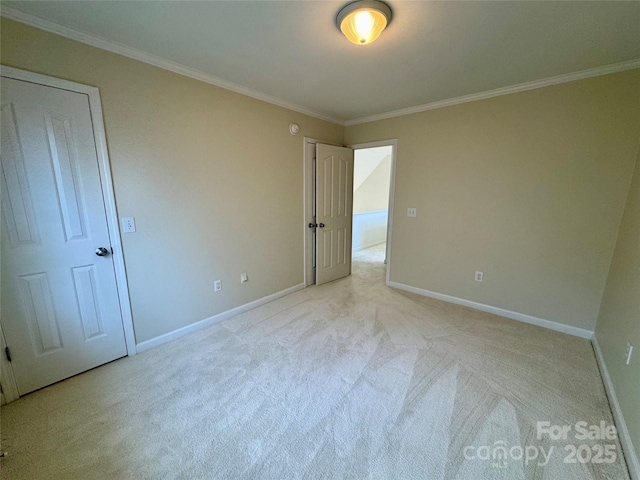 spare room featuring light colored carpet, ornamental molding, and baseboards