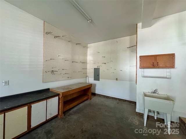 bathroom featuring unfinished concrete flooring, electric panel, and a workshop area