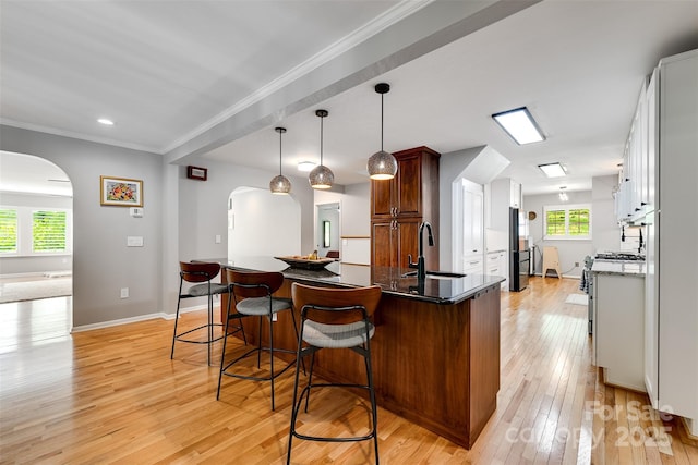 3407 Patton Rd, Franklin, NC 28734 - kitchen featuring arched walkways, a sink, light wood-type flooring, a breakfast bar, and crown molding