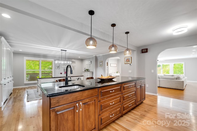 3407 Patton Rd, Franklin, NC 28734 - kitchen featuring arched walkways, a sink, light wood finished floors, a kitchen island, and brown cabinets
