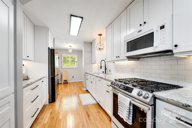 3407 Patton Rd, Franklin, NC 28734 - kitchen with white microwave, stainless steel range with gas stovetop, freestanding refrigerator, light wood finished floors, and white cabinets