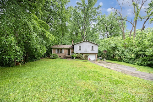 split level home with asphalt driveway, an attached garage, a front lawn, brick siding, and a chimney