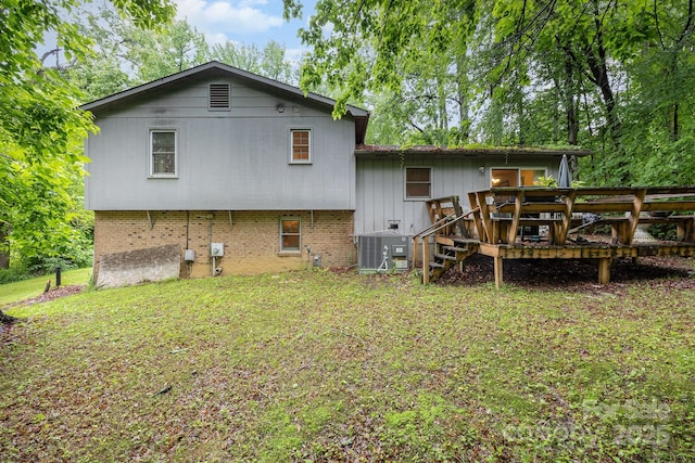 rear view of house with central air condition unit, a wooden deck, a yard, and brick siding