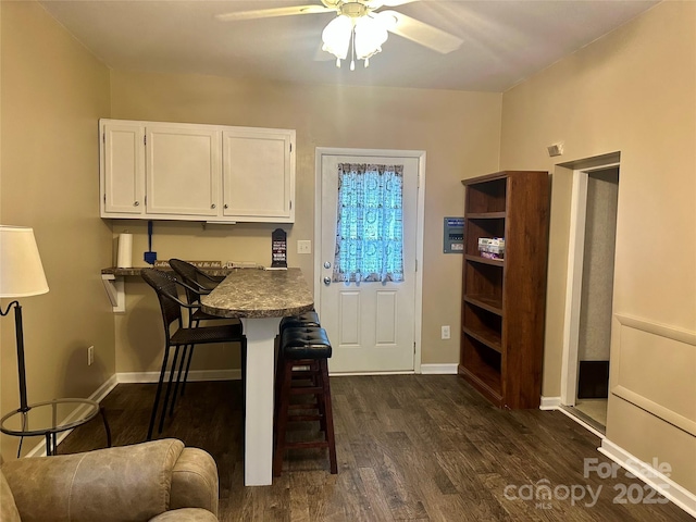 dining room featuring dark wood-style floors, ceiling fan, and baseboards