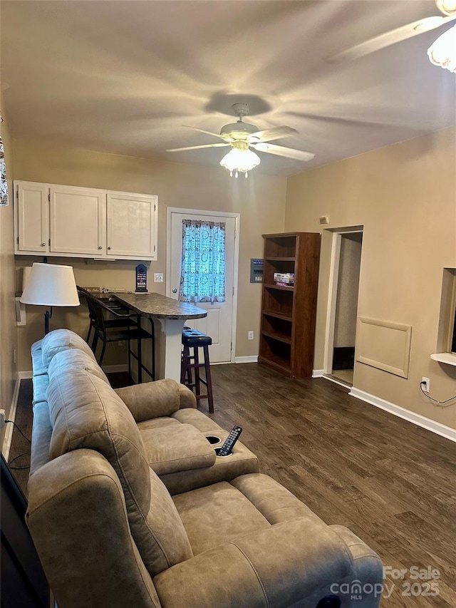 living room with a ceiling fan, baseboards, and dark wood-style flooring