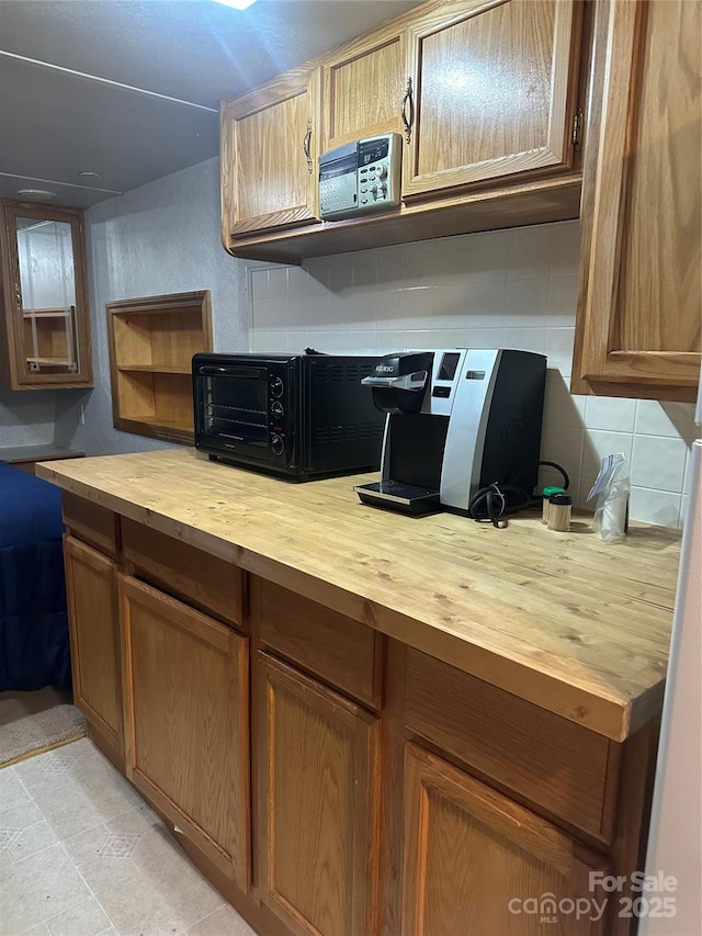 kitchen featuring butcher block countertops, decorative backsplash, open shelves, and brown cabinets