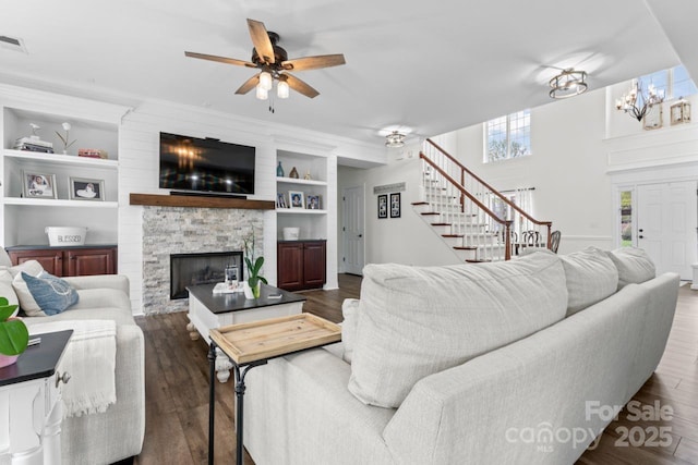 1016 Spanish Moss Rd, Indian Trail, NC 28079 - living room featuring stairs, a stone fireplace, ceiling fan, built in features, and wood finished floors