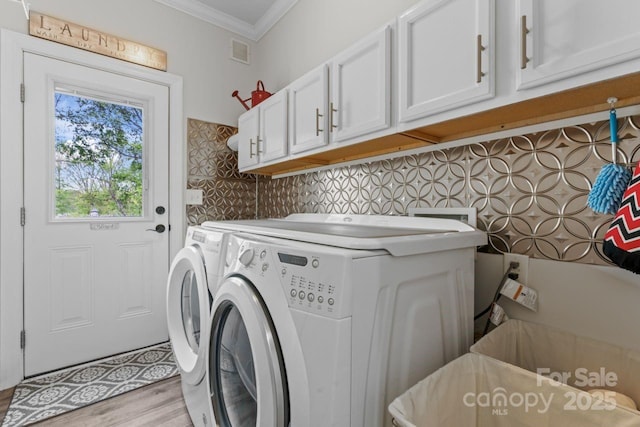 1016 Spanish Moss Rd, Indian Trail, NC 28079 - clothes washing area featuring cabinet space, ornamental molding, washing machine and dryer, and light wood-style floors
