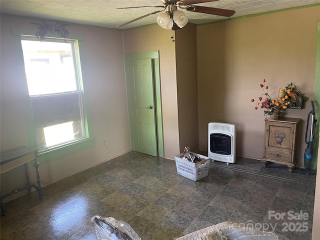 unfurnished living room featuring heating unit and a ceiling fan