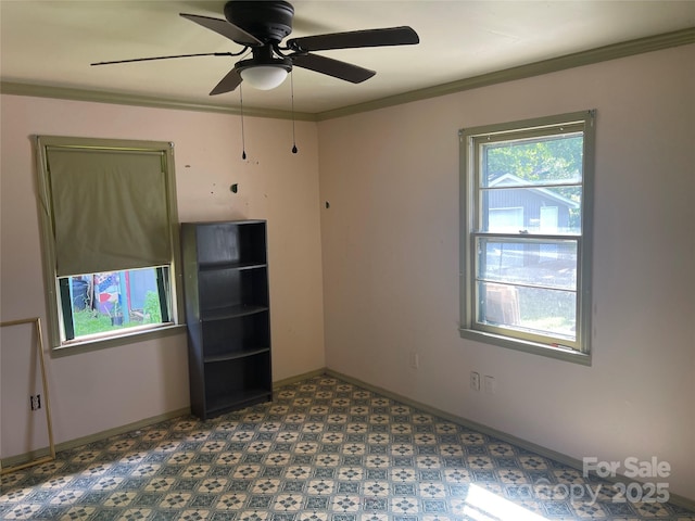 empty room featuring a ceiling fan, crown molding, and baseboards
