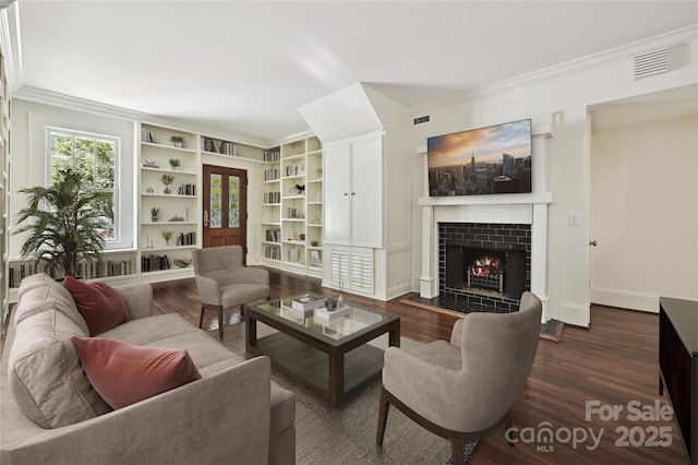 living area with crown molding, dark wood-type flooring, a fireplace, built in features, and baseboards