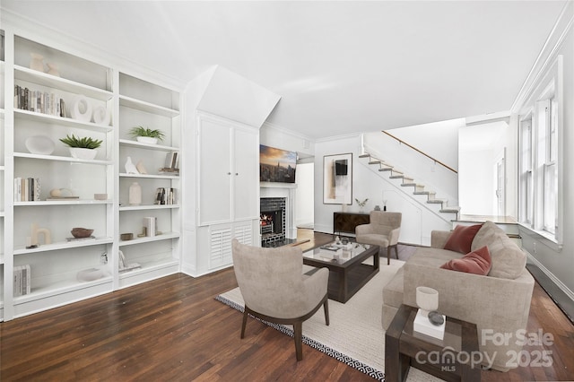 living room featuring dark wood-style floors, stairway, a fireplace, baseboards, and built in shelves