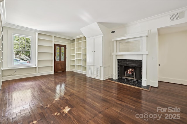 unfurnished living room featuring hardwood / wood-style flooring, built in features, ornamental molding, a tiled fireplace, and french doors