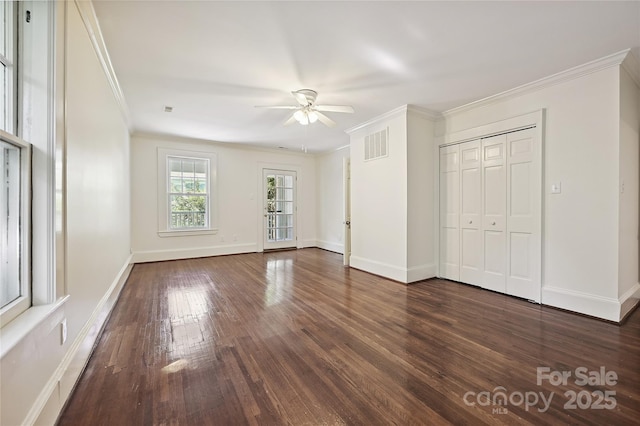 unfurnished bedroom featuring ornamental molding, dark wood finished floors, baseboards, a closet, and a ceiling fan
