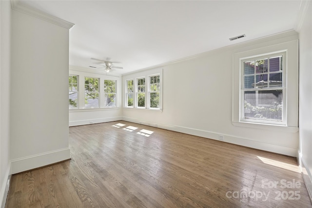 spare room with crown molding, baseboards, ceiling fan, and wood finished floors