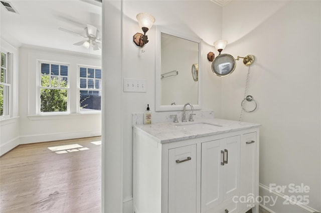 bathroom featuring wood finished floors, baseboards, a ceiling fan, vanity, and ornamental molding