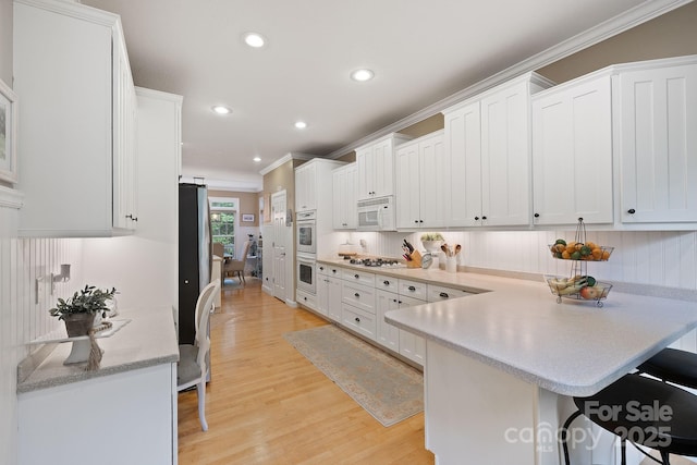 226 Duncan Estate Dr, Fletcher, NC 28732 - kitchen featuring white appliances, ornamental molding, a peninsula, a kitchen breakfast bar, and light wood finished floors