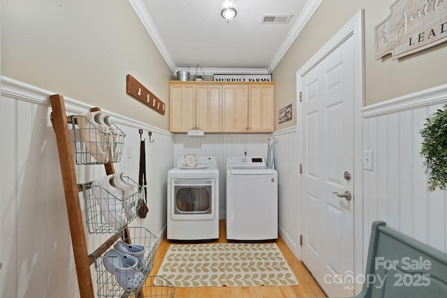 226 Duncan Estate Dr, Fletcher, NC 28732 - laundry room with crown molding, separate washer and dryer, cabinet space, wainscoting, and light wood-style floors
