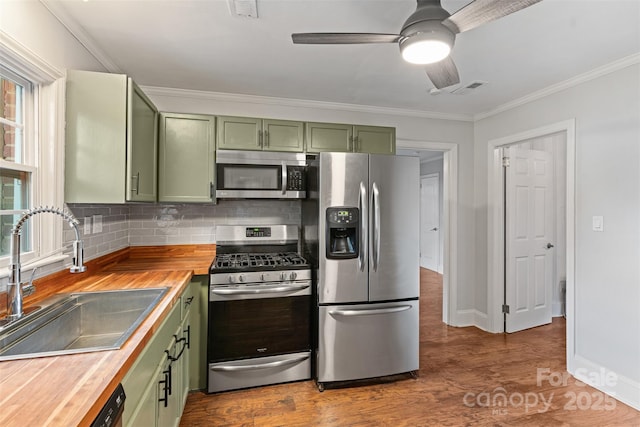 2953 Enfield Rd, Charlotte, NC 28205 - kitchen featuring green cabinets, appliances with stainless steel finishes, a sink, wooden counters, and backsplash